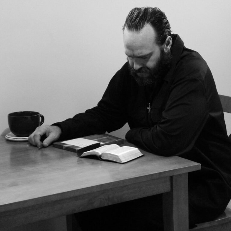 Persona leyendo la Biblia en una mesa, imagen contextual de lectura personal
